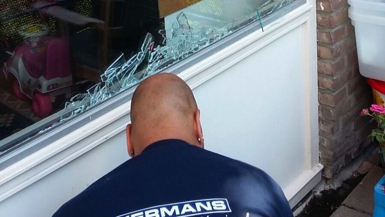 Een glaszetter vervangt het vernielde raam Beeld Hanneloes Pen