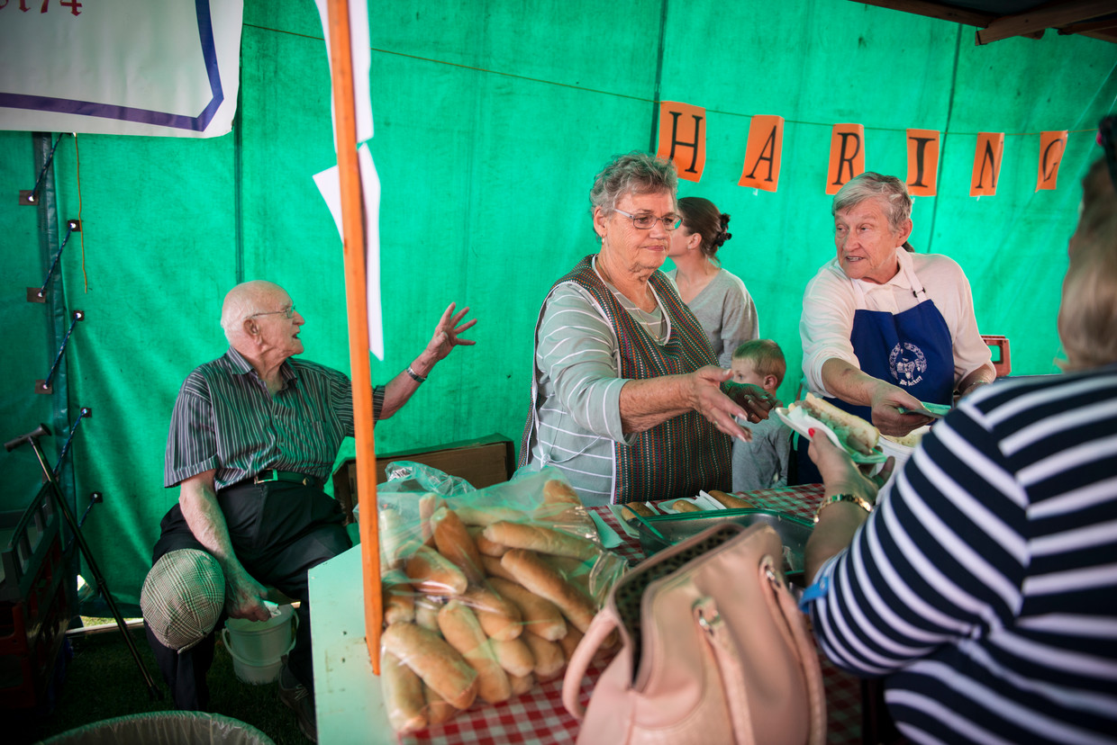 Nora de Rijk-Van der Laan (rechts) verkoopt haring op de Oranjemarkt. Haar man Jan de Rijk (links) zit naast de koelbox met vis. Beeld Bram Lammers