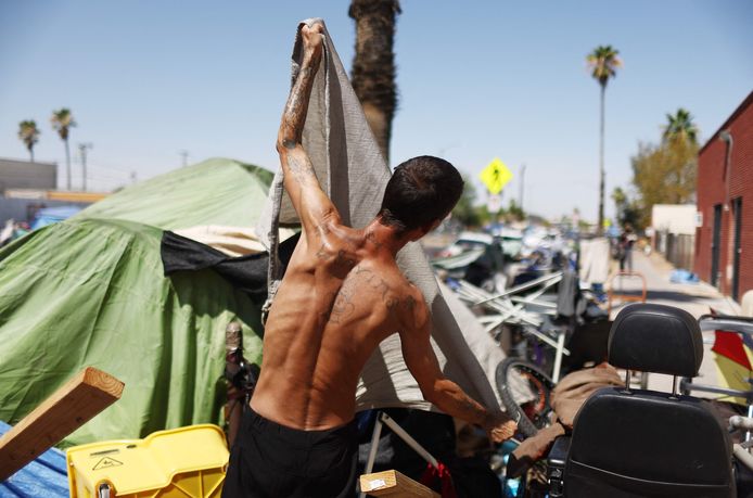 Dakloze past tent aan om de schaduw te helpen vergroten in deel van de 'The Zone', het grootste daklozenkamp van Phoenix.