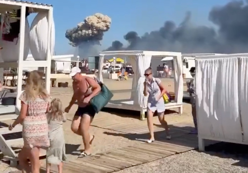 Russische toeristen die een strand op de Krim ontvluchten terwijl er zich explosies voordoen op de nabijgelegen vliegbasis van Novofedorivka.