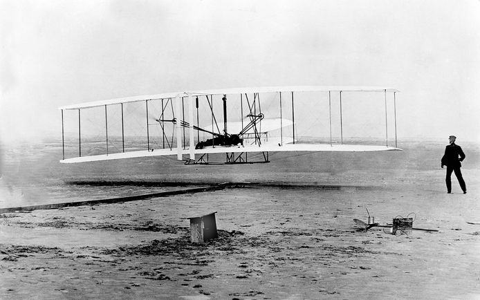 Wilbur Wright ziet vanop de grond hoe zijn broer Orville op 17 december 1903 de eerste geslaagde gemotoriseerde vlucht ooit maakt in Kitty Hawk, North Carolina. Het vliegtuig, de Wright Flyer, bleef twaalf seconden in de lucht en legde een afstand van bijna 37 meter af.