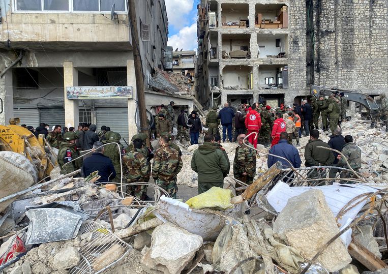 Russische militaire politie, het Syrische leger en de Syrische politie staan voor een verwoest gebouw in Aleppo terwijl de zoektocht naar overlevenden in de nasleep van de aardbeving doorgaat. Beeld REUTERS