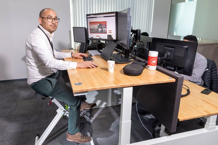 Raymond Pattipeilohy zit bij PwC achter zijn bureau op een hometrainer.