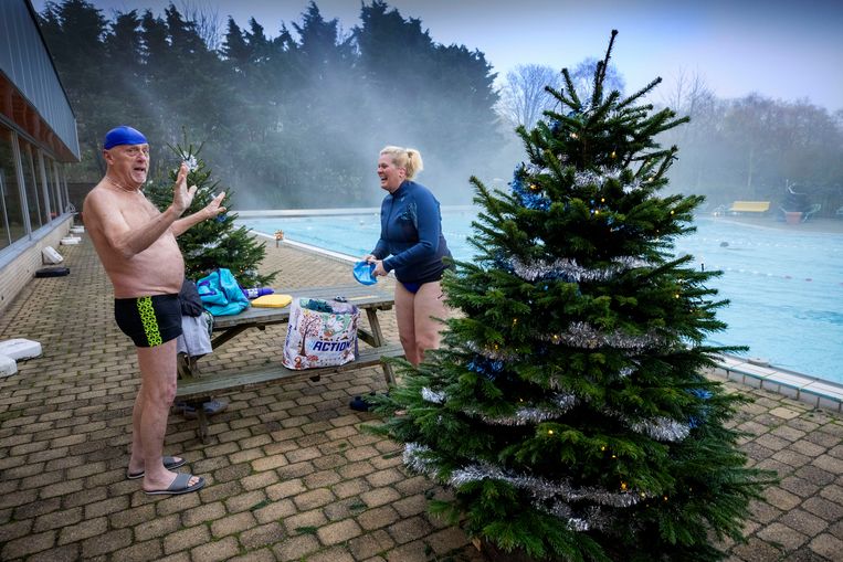 De zwemkameraden Cees den Hollander en Anette van Os kleden zich om tussen de kerstbomen. Zelfs zwemmen onder het vriespunt is voor hen niet te gek. Beeld Werry Crone
