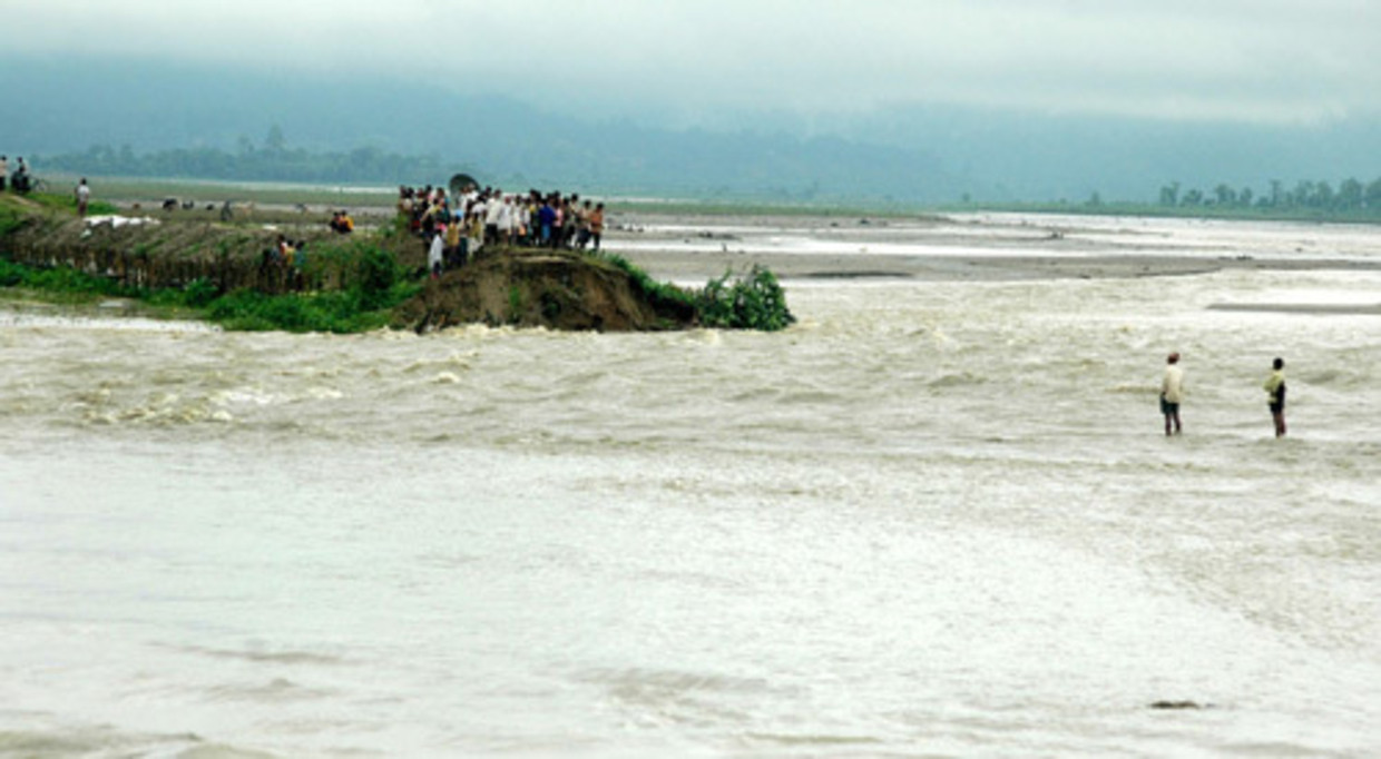 Inwoners van een dorp in de Indiase deelstaat Assam kijken maandag naar het verwoestende water. In Assam zijn elf mensen omgekomen en ruim vier miljoen mensen voor het water op de vlucht geslagen. De moesson heeft dit jaar hard toegeslagen in het zuiden en zuidwesten van Nepal en het noordoosten van India. (AFP) Beeld 