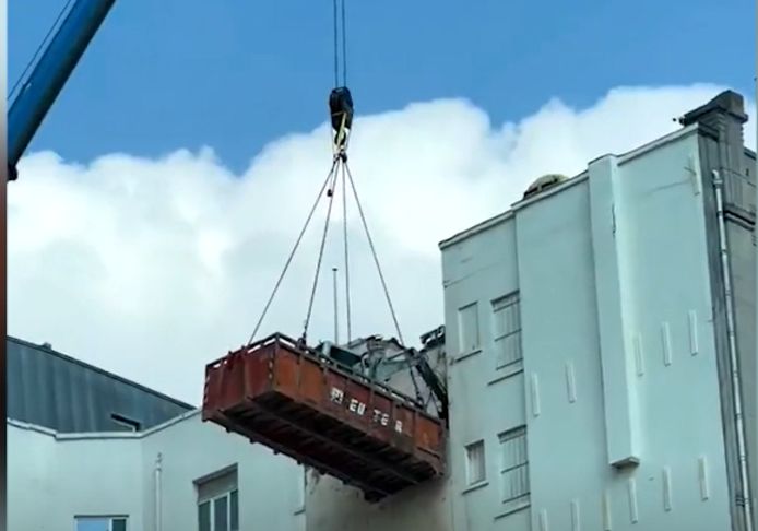 Bulldozer ruimt puin vanuit zwevende container.