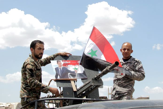 Syrische soldaten met de nationale vlag een foto van de Syrische president Bashar al-Assad in een recent ingenomen wijk in Zuid-Damascus deze week.
