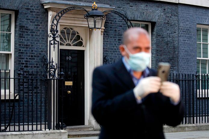 Een man met een mondmasker in Downing Street, waar premier Johnson in quarantaine zit.
