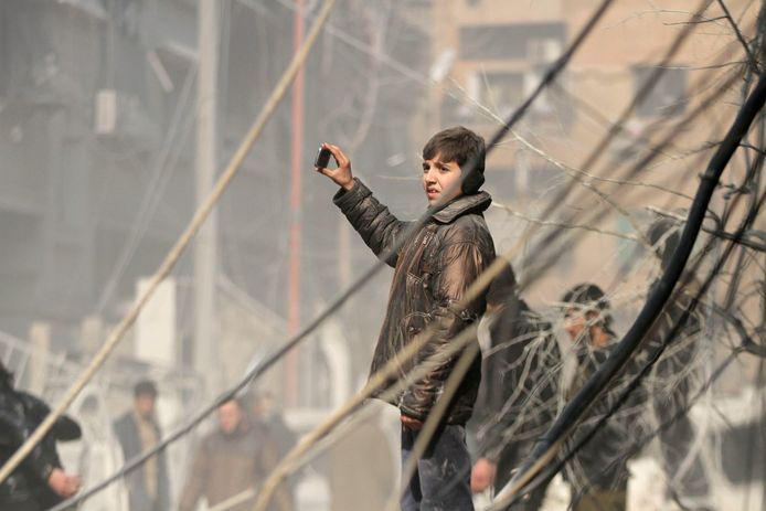 A boy uses his phone to film a damaged site after what activists said were air strikes by forces loyal to Syria's President Bashar al-Assad in the Duma neighborhood of Damascus January 21, 2015. REUTERS/ Mohmad Badra  (SYRIA - Tags: POLITICS CIVIL UNREST CONFLICT)