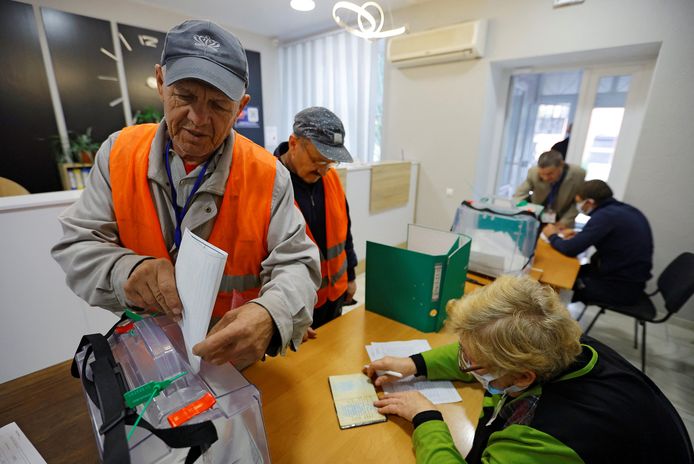 Twee gemeentewerkers brengen hun stem uit in Zaporizja.