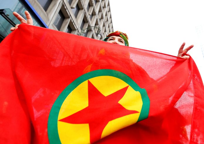 Een vrouw met een vlag van de PKK (Koerdische Arbeiderspartij).
