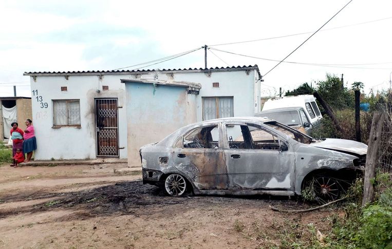 Twee Zimbabwaanse vrouwen bij hun huisje in een wijk bij Durban, dat met benzinebommen werd aangevallen door Zuid-Afrikaanse relschoppers. Ook de auto's werden in de brand gestoken. Beeld afp