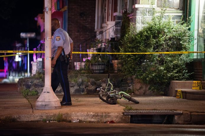 Een politieagent loopt weg van het fietsje van een kind dat in de benen geschoten werd tijdens de schietpartij in Philadelphia.