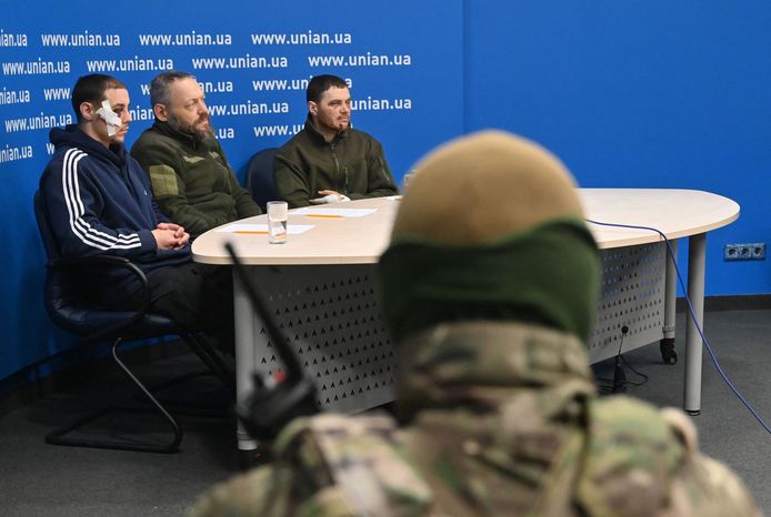 Een Oekraïense soldaat bewaakt drie krijgsgevangen Russische officieren tijdens een persconferentie in Kiev.