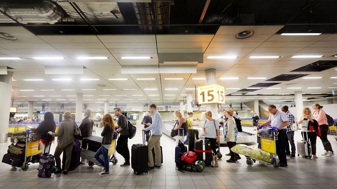 Reizigers die zijn aangekomen op Schiphol staan in de rij voor voor controle van de douane.