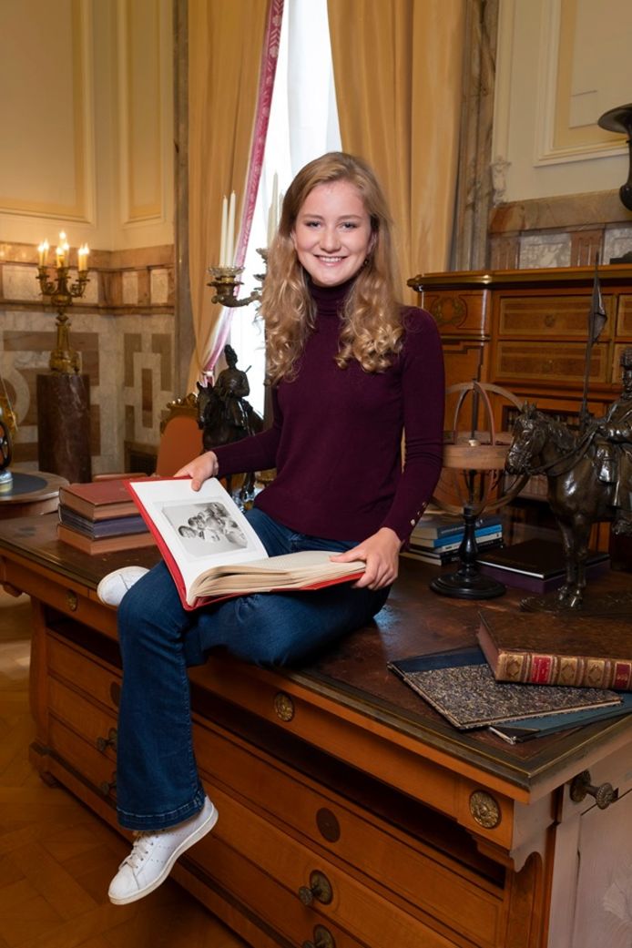 Elisabeth op een bureau met een oud fotoalbum waarin een foto te zien is van haar vader Filip als peuter in haar handen.