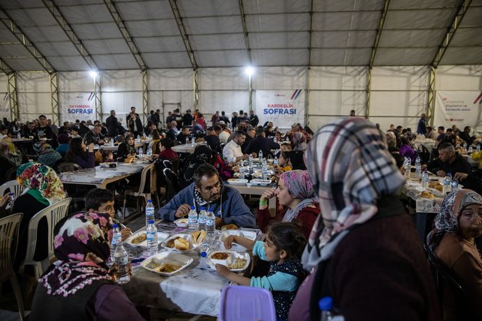 Overlevers van de aardbevingen eten 's avonds samen in een tent na het vasten op de laatste dag van de ramadan in Adiyaman, Turkije. Beeld van 20 april.