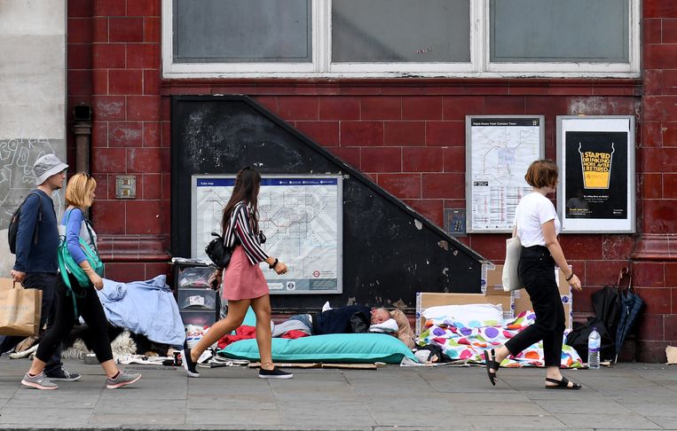 Voorbijgangers wandelen langs een dakloze man in Londen. Beeld EPA