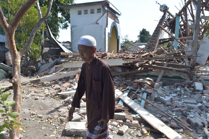 Een inwoner van Lombok loopt een moskee voorbij die het begaf tijdens de  aardbeving van 12 augustus. Al sinds 29 juli wordt het eiland zwaar getroffen.