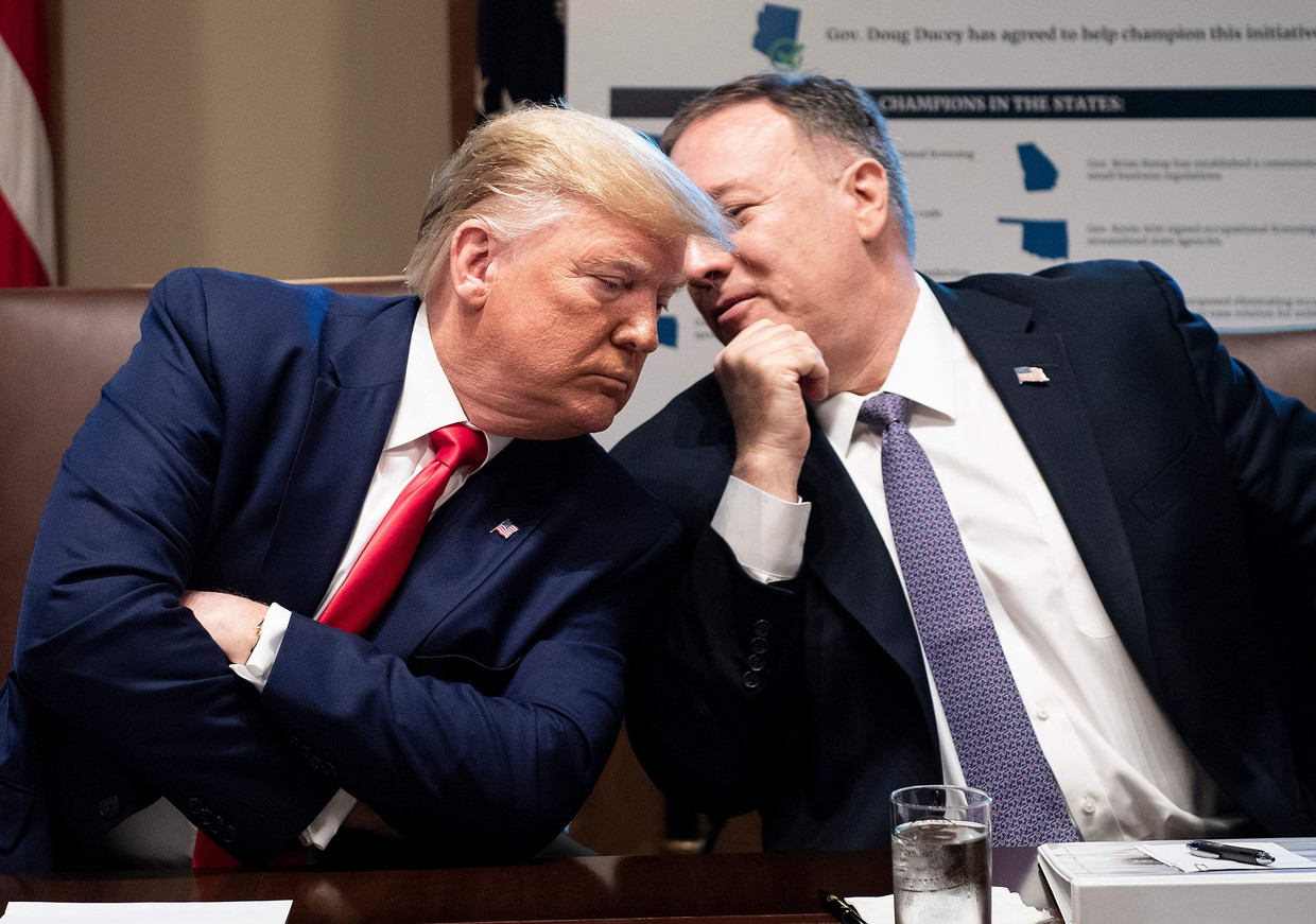 De Amerikaanse president Trump luistert naar zijn buitenlandminister Mike Pompeo die iets in zijn oor fluistert. Beeld AFP