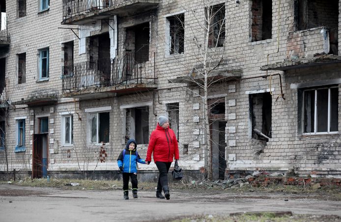 Inwoners van een klein stadje in de Donetsk-regio lopen lang een oud vervallen gebouw.