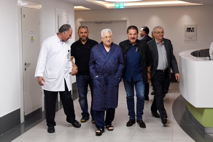 De Palestijnse president Mahmoud Abbas (midden, met kamerjas aan) maakt een wandelingetje door de gang van het ziekenhuis.