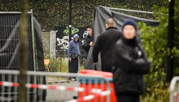 Een vluchteling kijkt toe hoe er na de bestorming hekken rond de noodopvang in Woerden worden gezet