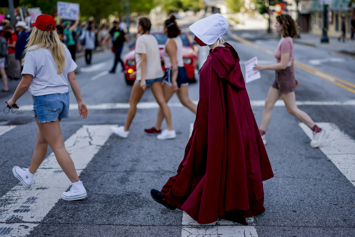 Een betoger refereert aan de herkenbare rode outfit in de serie 'The Handmaid's Tale', waarin vruchtbare vrouwen slechts gezien worden als een middel om voort te planten. Beeld ANP / EPA