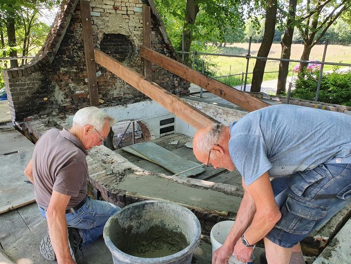 Wim Bartholomeus (links) en Leo Coppens (rechts ) zijn bezig met het aansmeren van de bovenkant van het metselwerk waarop de muurplaten komen.