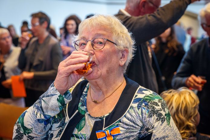 Mevrouw Van Dijk-Kooiker heeft zojuist haar lintje gekregen - en een bijpassend oranjebittertje.
