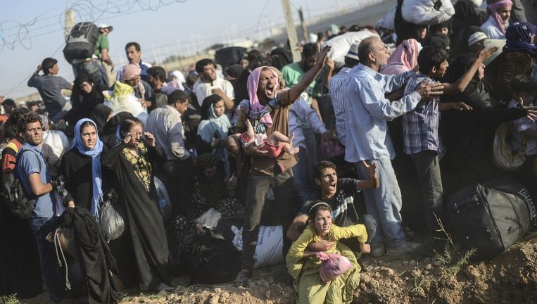 Syriërs vluchten zondag bij Akçadale naar Turkije via kapotte hekken en gaten in de grond. Beeld AFP