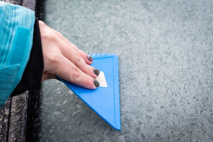 Een automobiliste krabt haar autoruiten schoon alvorens zij gaat rijden. Op het rijden met bevroren autoruiten staan hoge boetes.
