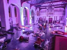 Niet stil op de kerkbankjes zitten, maar languit op je yogamatje in een donkere Laurenskerk