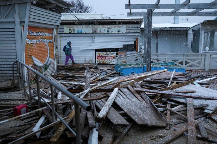 Une femme passe devant des constructions endommagées sur une plage touchée par une puissante tempête à Yevpatoriya, en Crimée, le 27 novembre 2023.