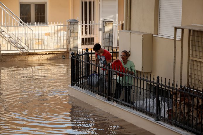 Inwoners proberen met emmers het water water uit hun huizen te krijgen. Beeld uit Larissa.
