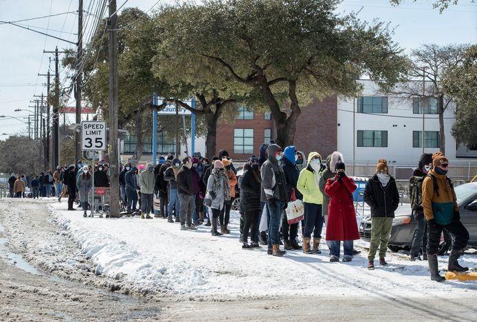 Mensen staan buiten in de kou in de rij om boodschappen te gaan doen.