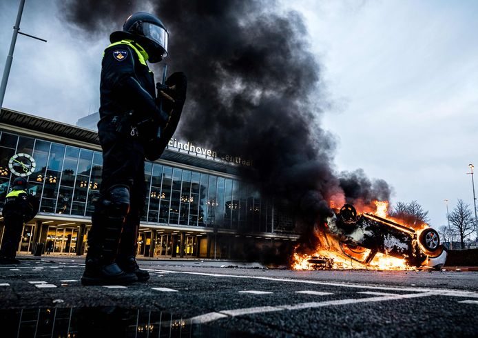 Een uitgebrande auto voor het Centraal Station van Eindhoven. Zondag mondde een demonstratie tegen de avondklok in Nederland uit in hevige rellen.