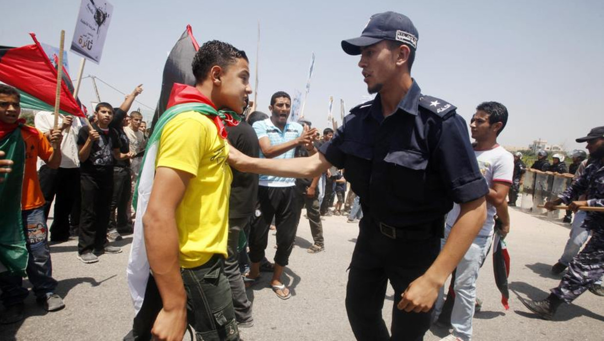Een demonstrant wordt tegengehouden door een Palestijnse politieagent Beeld reuters
