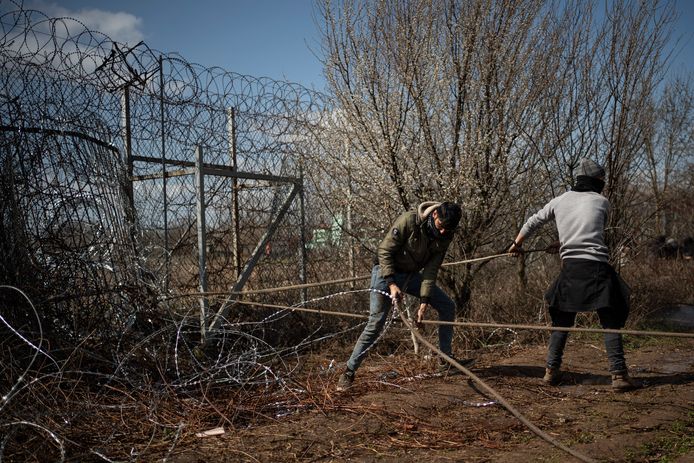 Migranten proberen het hek kapot te krijgen.