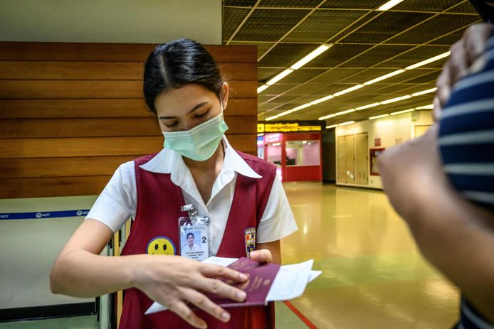Luchthavenmedewerkers dragen mondmaskers op de luchthaven van Bangkok.