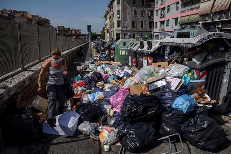 Een inwoner van Rome worstelt zich langs een berg vuilnis. De Italiaanse hoofdstad kampt al lange tijd met vuilnisproblemen. Beeld Getty Images