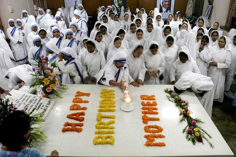 Nonnen herdenken de 99ste verjaardag van Moeder Teresa bij haar graftombe met een gebed. (EPA) Beeld 