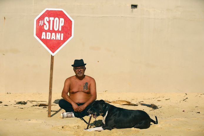 Een strandganger in Sydney demonstreert tegen de beoogde Carmichael-kolenmijn.