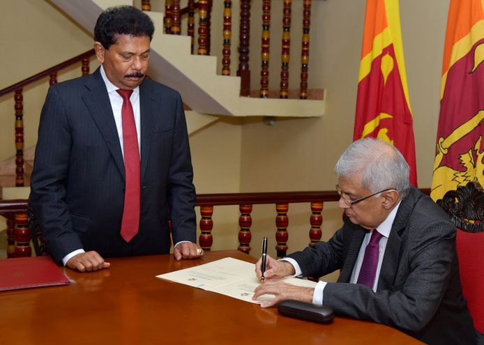De Sri Lankaanse premier Ranil Wickremesinghe (R) ondertekende een document na het afleggen van de eed als interim-president van Sri Lanka voor opperrechter Jayantha Jayasuriya.