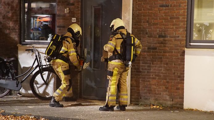 De brandweer zet een kettingzaag in een deur aan de Raamstraat in Deventer.