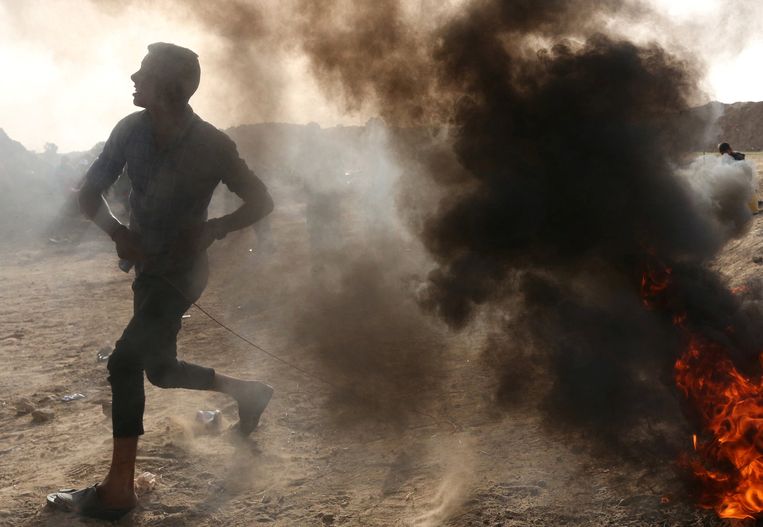 Een Palestijnse jongen gooit stenen in de richting van Israëlische soldaten aan de grens in Gaza. Beeld REUTERS