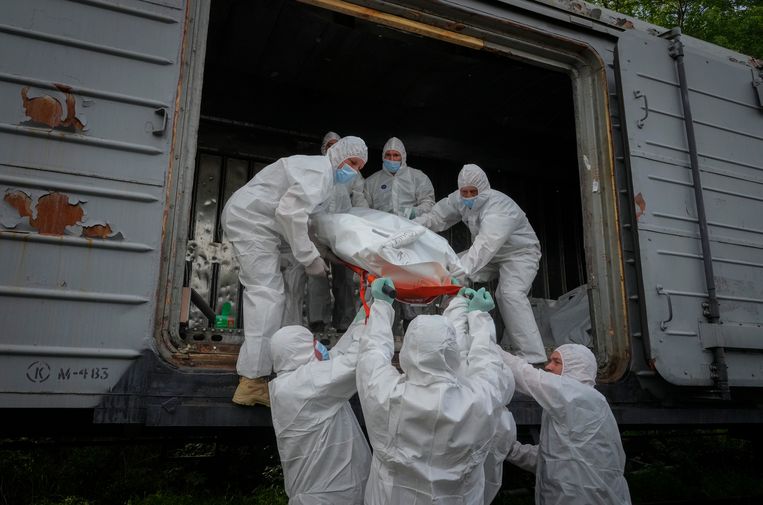 Oekraïners laden de lichamen van dode Russische soldaten in een treinwagon. Beeld AP