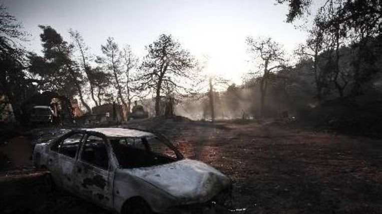 Een uitgebrande auto, maandag in de regio rond Athene. (AFP) Beeld 
