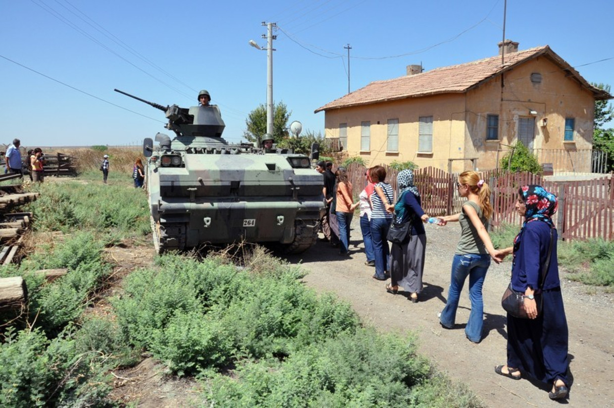 Een vredesdemonstratie, begin augustus, in de Turkse grensplaats Mardin, waar dit weekeinde twee Nederlanders werden opgepakt. Turkse soldaten kijken toe vanuit een pantservoertuig. Beeld afp