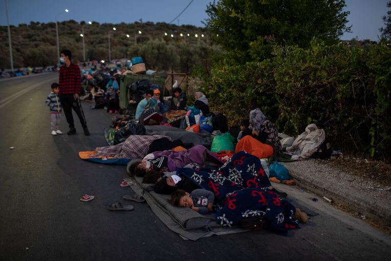 Migranten slapen op de weg vlakbij het afgebrande kamp Moria op het eiland Lesbos.  Beeld AP